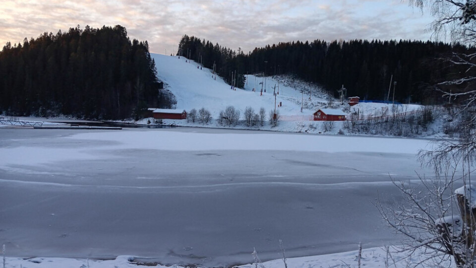 View of a Frozen lake with a ski slope in the background