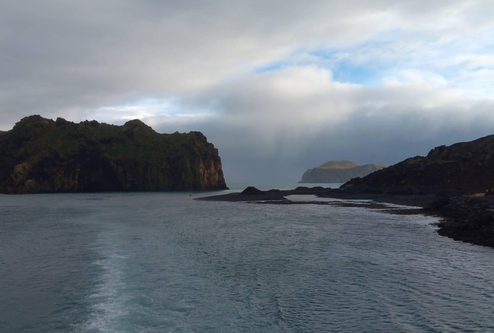 Rocky landscape sticking out of the water with cloud covered skies