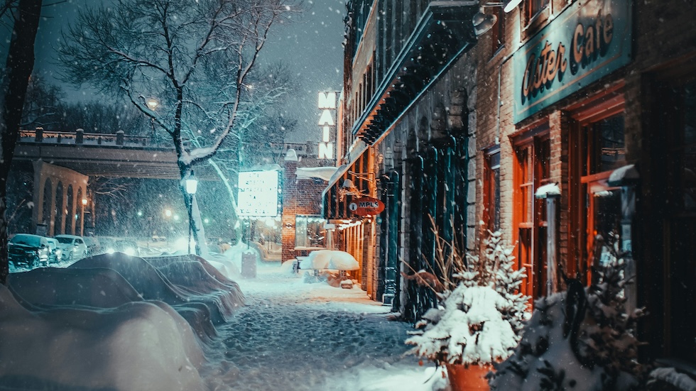 A snow covered street with shopes.