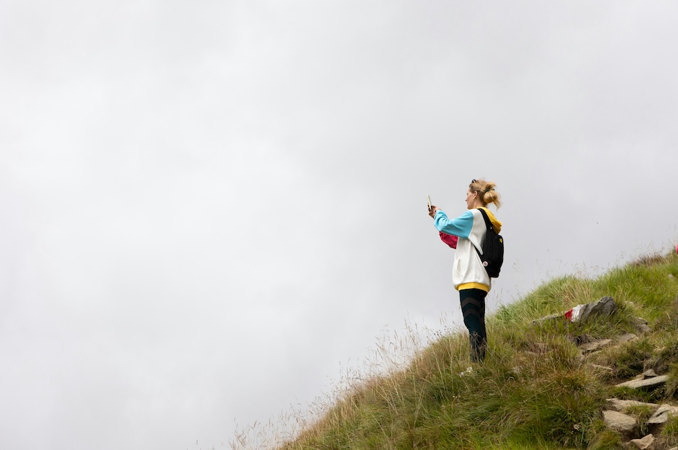 A woman on a hill, taking a picture of fog