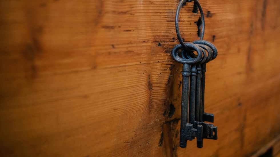 Old black keys on a hook with a wooden background